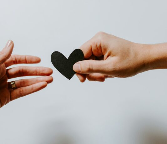 개인의 삶의 질을 결정 짓는 정신적 웰빙 person reaching black heart cutout paper