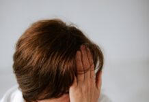 갱년기 증상 완화와 호르몬 건강 지키는 방법 a woman sitting on a bed holding her head in her hands