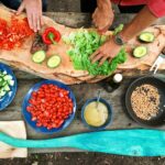 집밥의 재발견… 건강한 식탁 위한 ‘홈쿡 챌린지’ 열풍 person slicing green vegetable in front of round ceramic plates with assorted sliced vegetables during daytime
