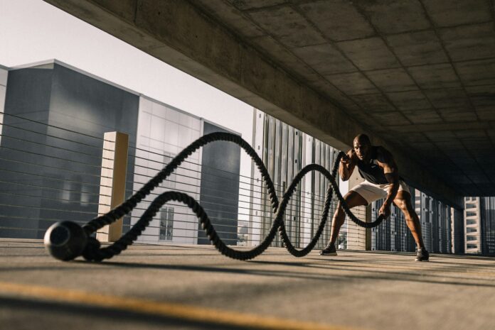 man exercising with battle ropes outdoors
